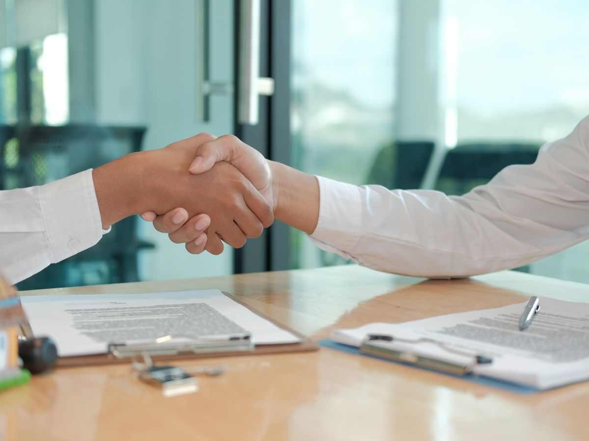 persone che si stringono la mano dopo aver firmato un contratto