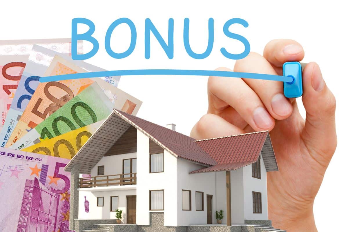 mano che con un evidenziatore azzurro scrive bonus, modellino casa e banconote euro